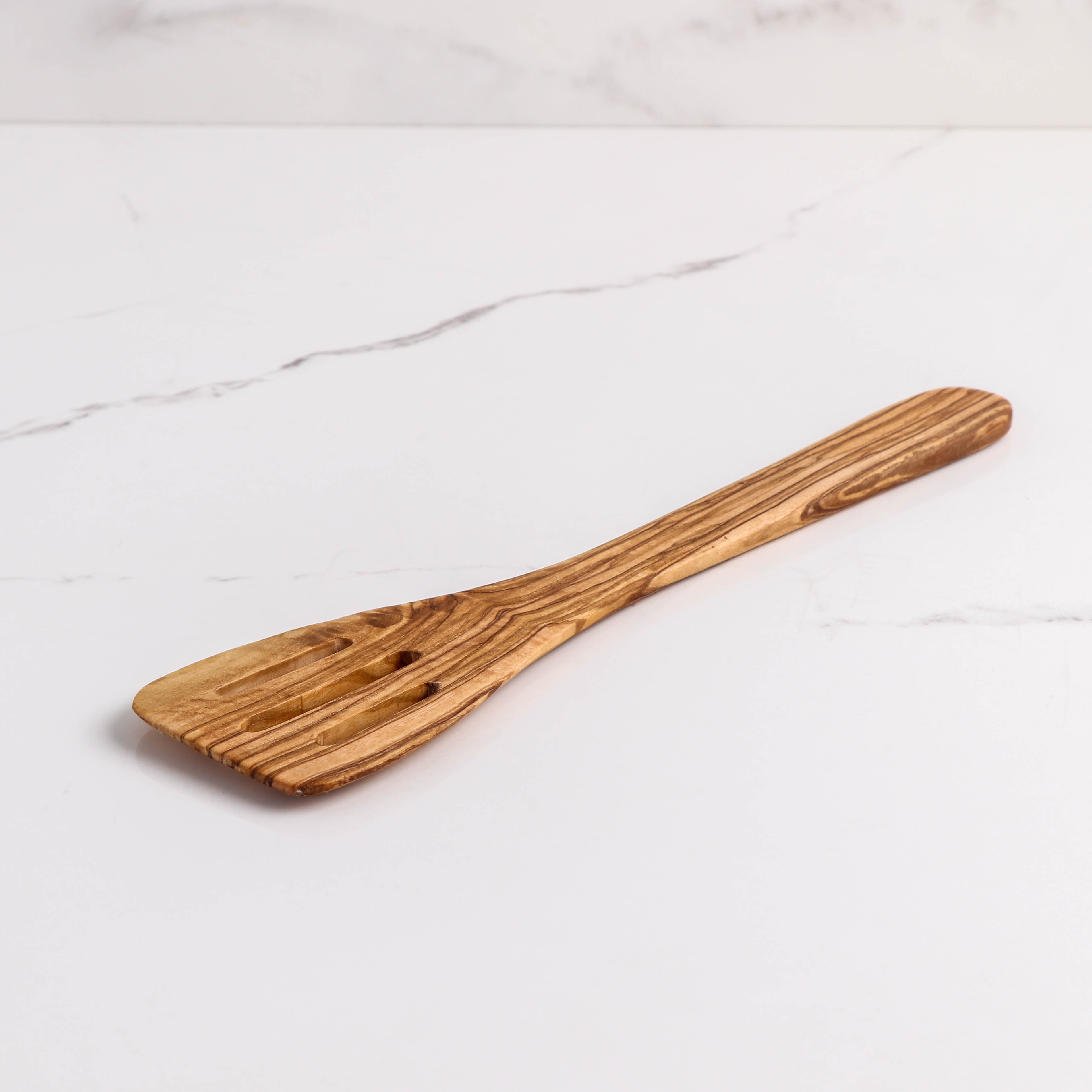 Handmade Olive Wood Slotted Spatula, a versatile cooking utensil perfect for flipping and draining. Crafted from durable olive wood, it's a unique, functional addition to any kitchen. Ideal for those who appreciate the beauty and practicality of wood kitchen utensils